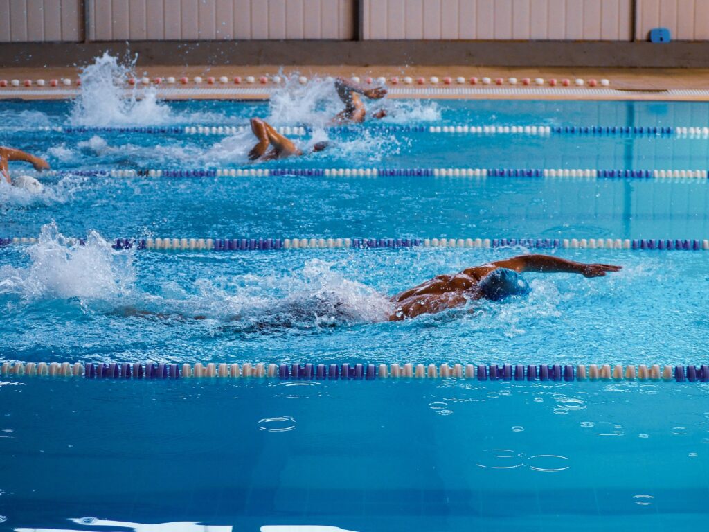 Swimmers in action during a race in an indoor swimming pool, showcasing athleticism.